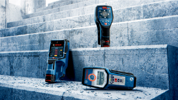 Three Bosch Professional measuring devices are lying on stone steps.