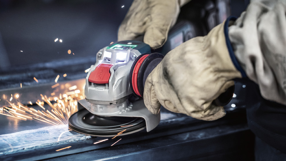 A gloved hand operates a Bosch angle grinder.