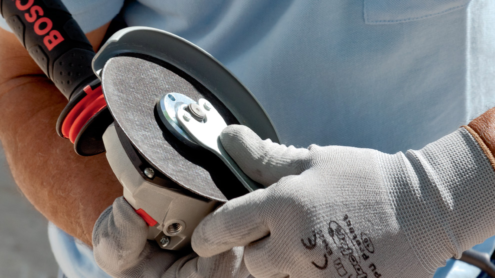 A person is holding a Bosch Professional grinding machine in their hand.