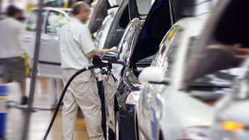 A worker is refueling a car in a workshop, several cars are ready.