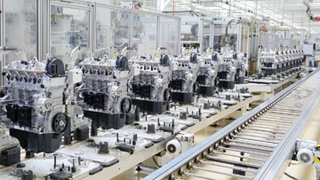 Several shiny engines are on a production line in a factory.