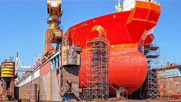 A large red ship is standing on a storage area with scaffolding.