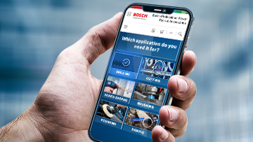 A hand holds a mobile phone displaying the Bosch Professional website.
