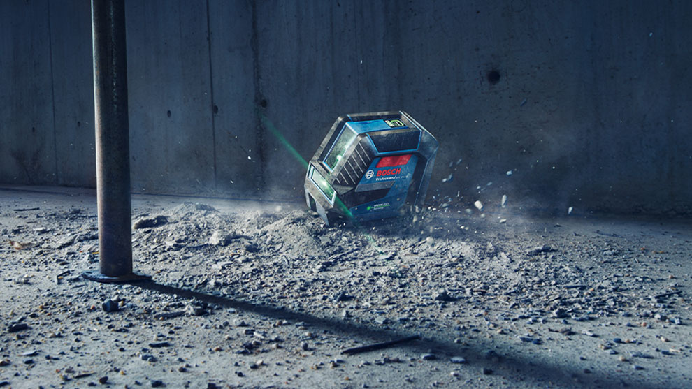 A blue Bosch Professional battery on dusty ground, surrounded by debris.