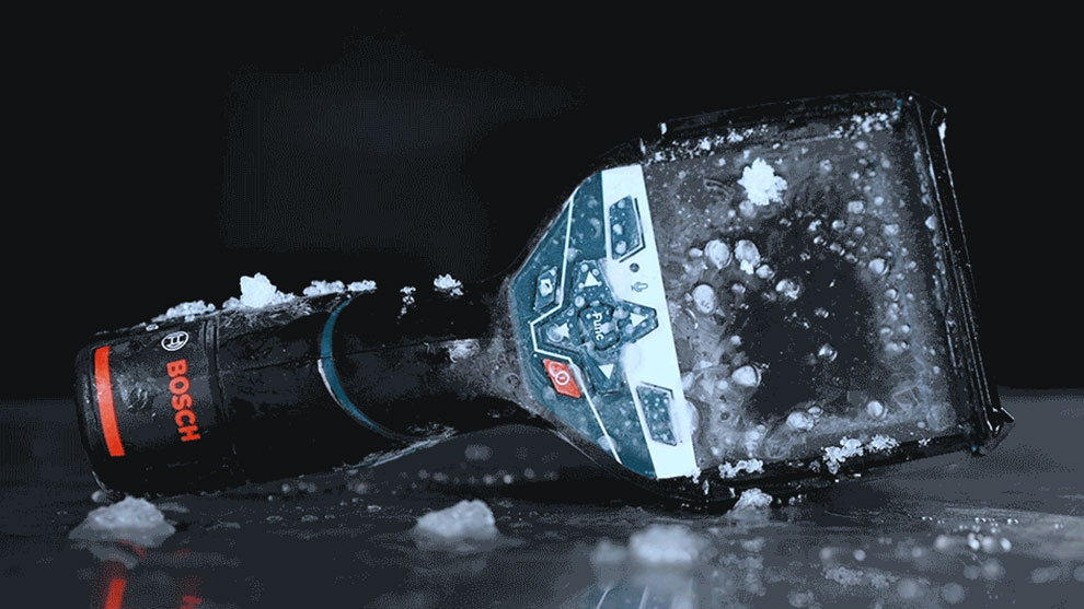 A Bosch Professional flashlight is lying in ice water, black and blue.