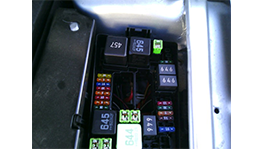 A fuse box with colorful fuses and relays in a car.