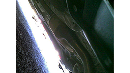 A view under a vehicle onto a shiny metal surface.