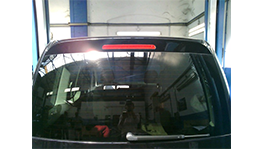 The rear view of a black vehicle in a workshop.