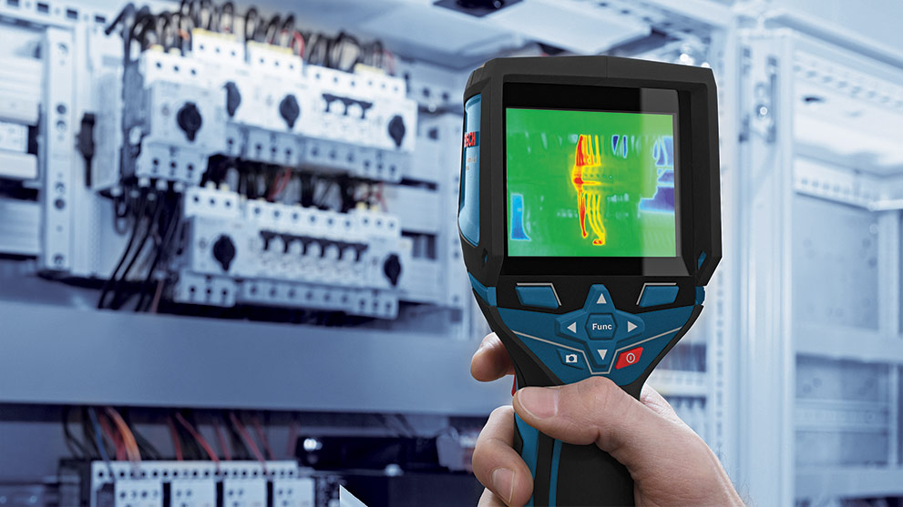 A Bosch Professional thermal imaging device is held in front of an electrical cabinet.