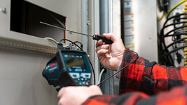 A craftsman in a checked shirt is using a Bosch Professional measuring device.