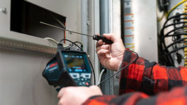A technician holds a Bosch Professional measuring device in front of a device.