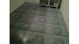Gray tiled floor in a room with white walls and grid shelving.