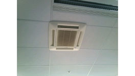 A white ceiling air conditioner installed on a bright ceiling.